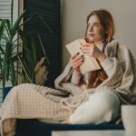 Red-haired,Woman,Sitting,On,The,Sofa,,Covered,With,A,Warm