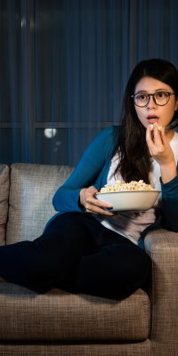 Young,Lovely,Girl,Holding,Popcorn,Box,And,Looking,At,Tv
