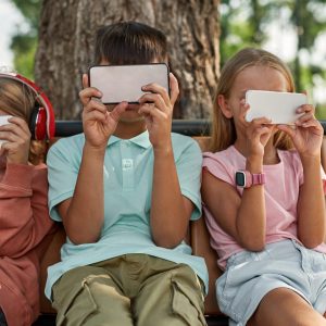 Obscure,Faces,Of,Children,Using,And,Watching,Smartphones,On,Wooden