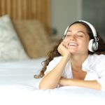 Happy,Woman,On,The,Bed,Listening,To,Music,With,Headphones