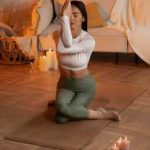 iemand die thuis yoga doet op een mat met kaarslicht of lampjes iemand die thuis yoga doet op een mat met kaarslicht of lampjes