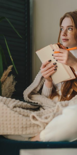 Red-haired,Woman,Sitting,On,The,Sofa,,Covered,With,A,Warm